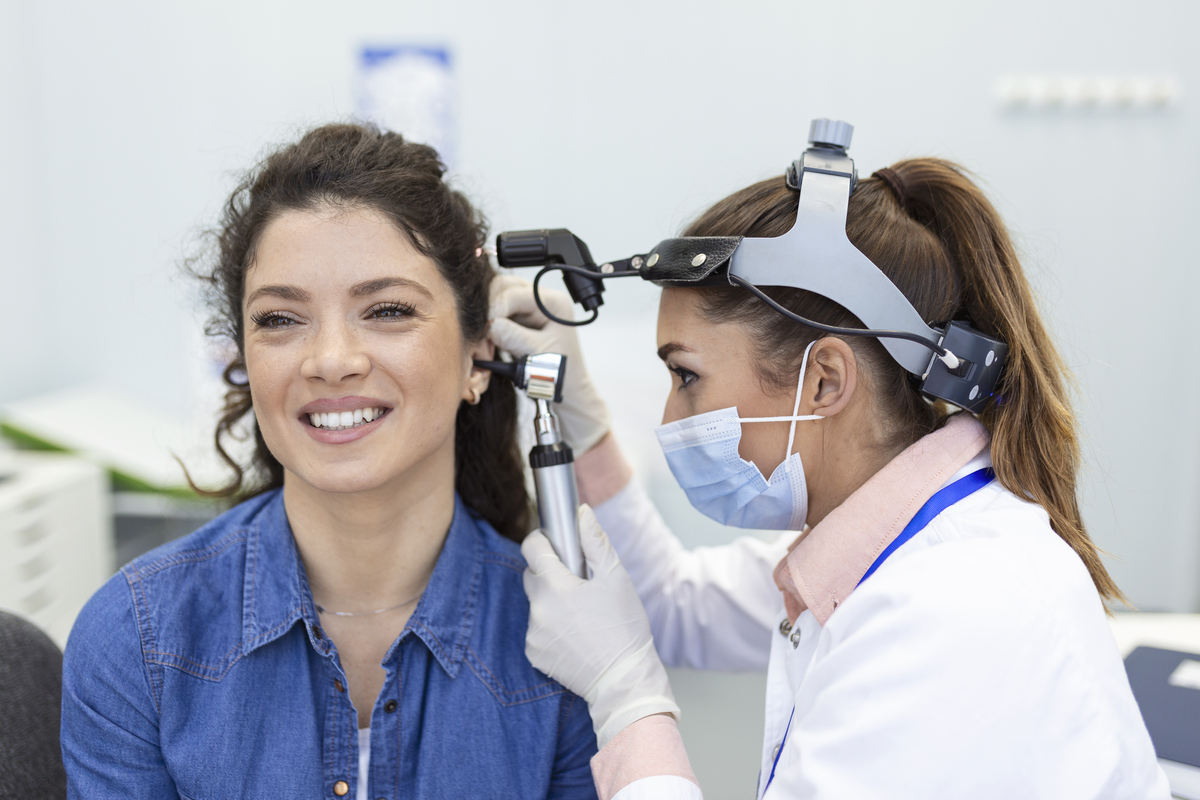 Hearing exam. Otolaryngologist doctor checking woman's ear using otoscope or auriscope at medical clinic. examen audicion medico otorrinolaringologo revisando oido mujer usando otoscopio o auriscopio clinica medica