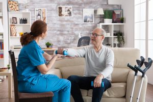 Enfermera haciendo tratamiento de fisioterapia a un adulto mayor